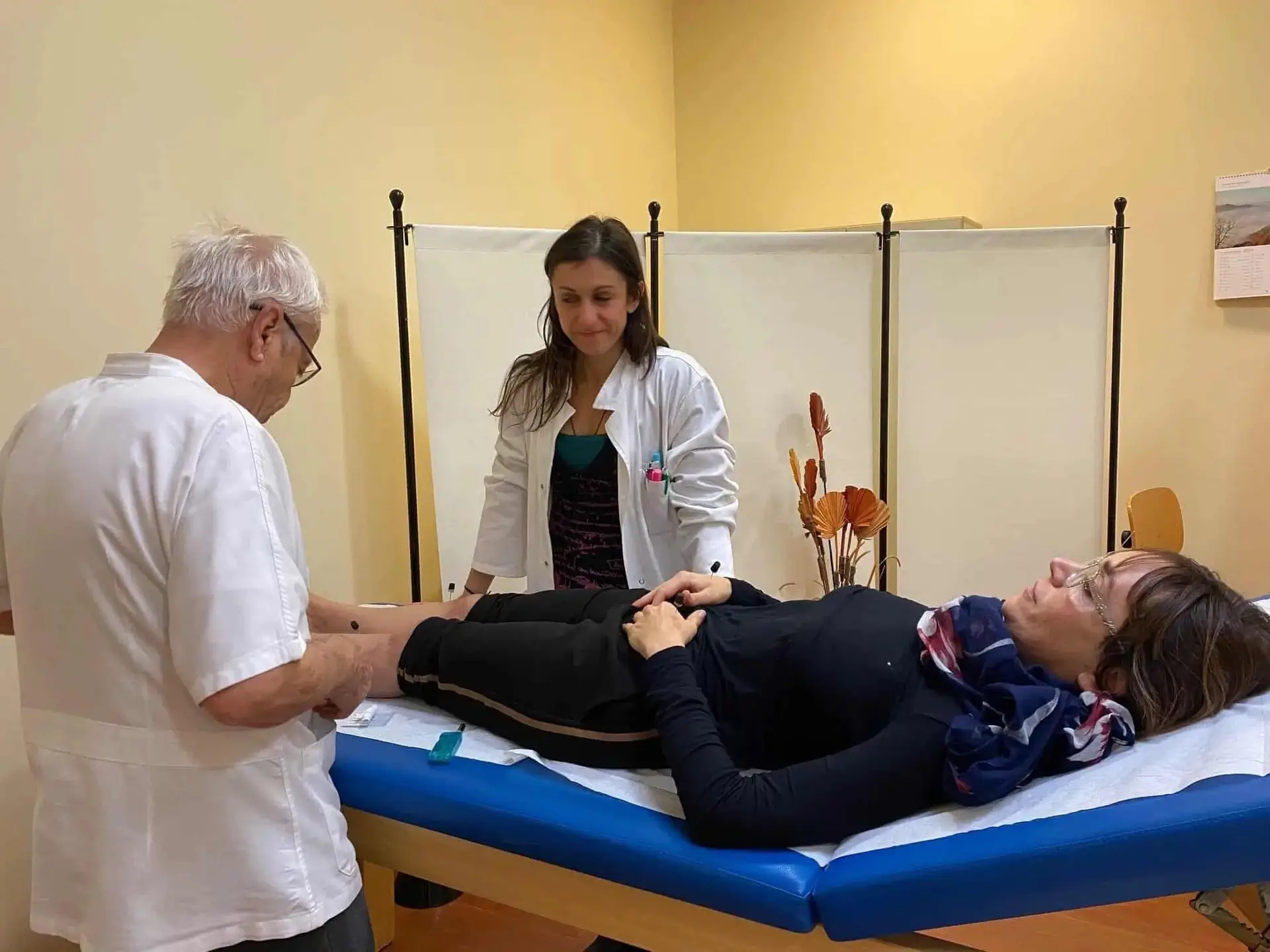 Esame del piede di una donna da parte di un medico in un ambulatorio di agopuntura, con Erika Francese e Giorgio Di Concetto.